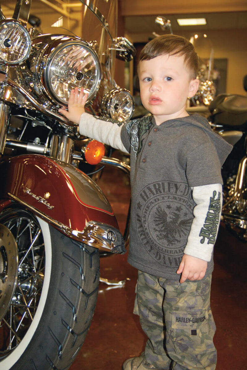2017 Harley-Davidson® a boy showing his MotorClothes® hoodie next to Harley-Davidson® motorcycle.