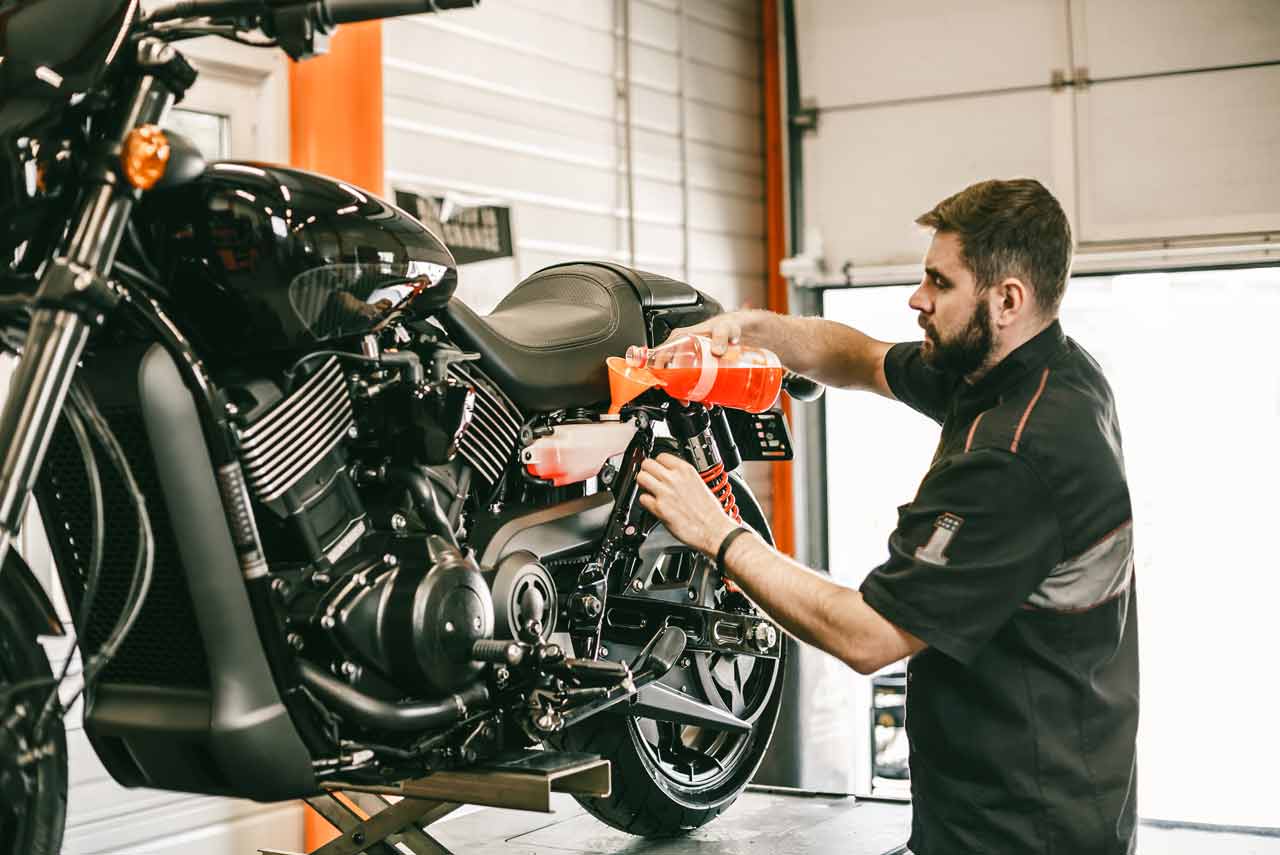 Harley-Davidson® technician adding fluid to motorcycle